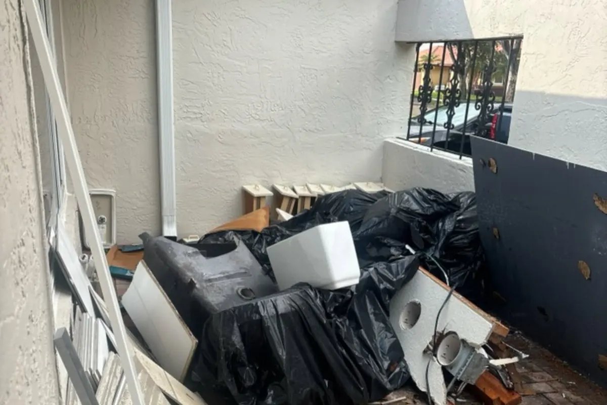 Old furniture, a TV and bags piled on a tiled patio before pickup