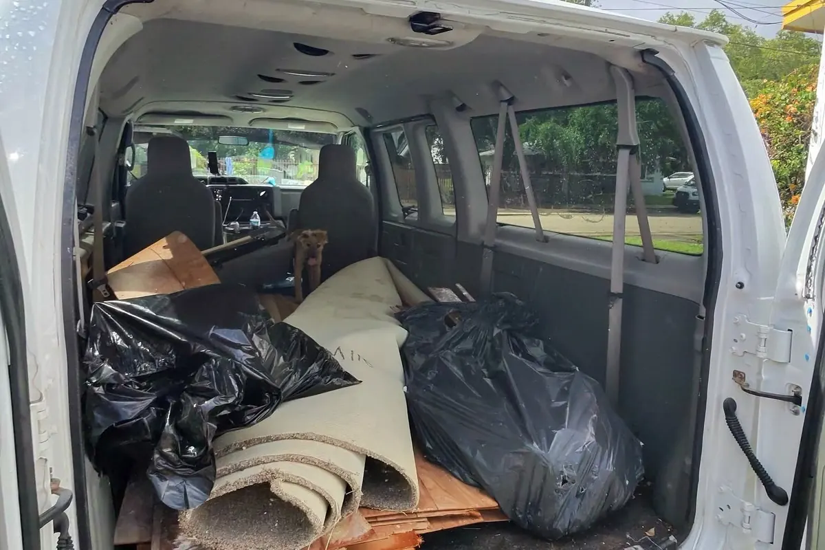 A cargo van loaded with bags, carpet and household junk