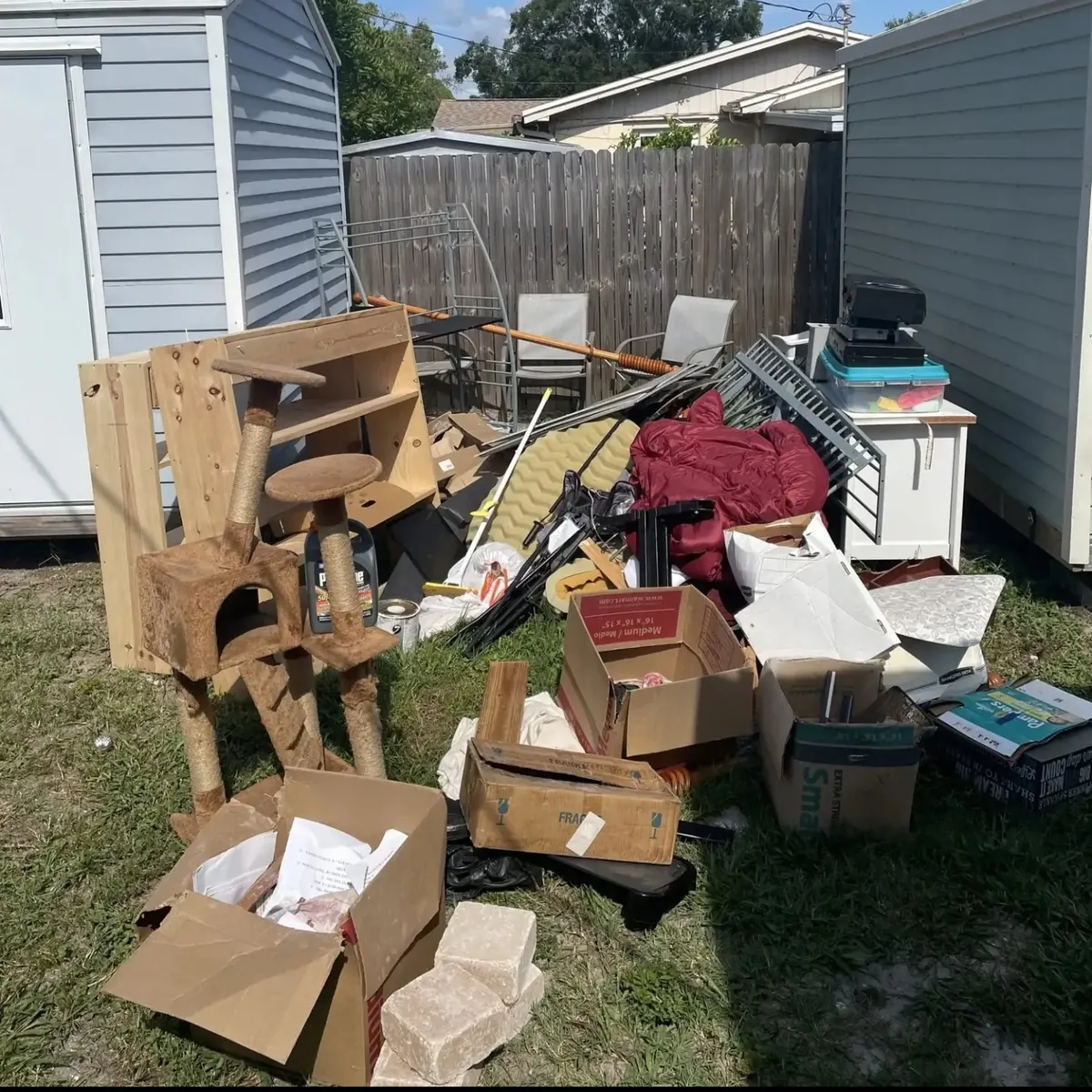 Shelving, boxes and old furniture piled in a backyard beside a shed